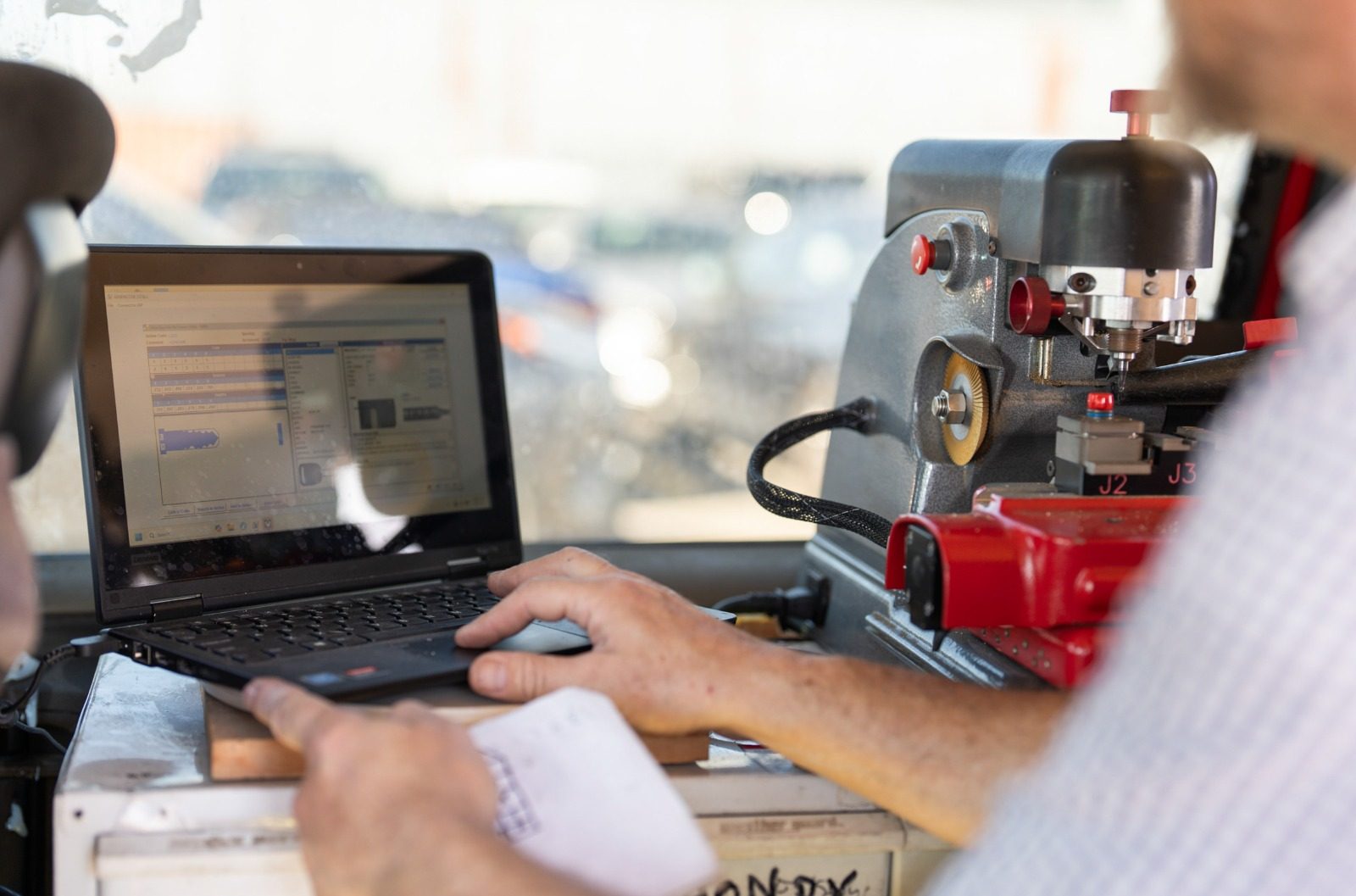 Mobile car locksmith working at a customer's car door beside the open van workshop in West Palm Beach